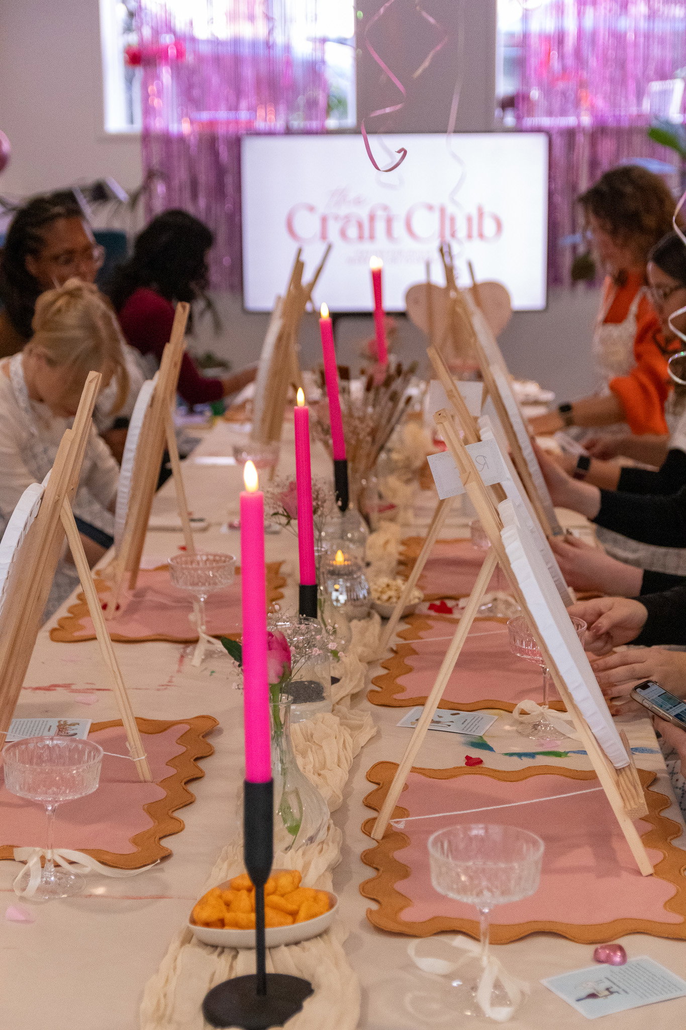 A group of women crafting together around a candlelit workshop table