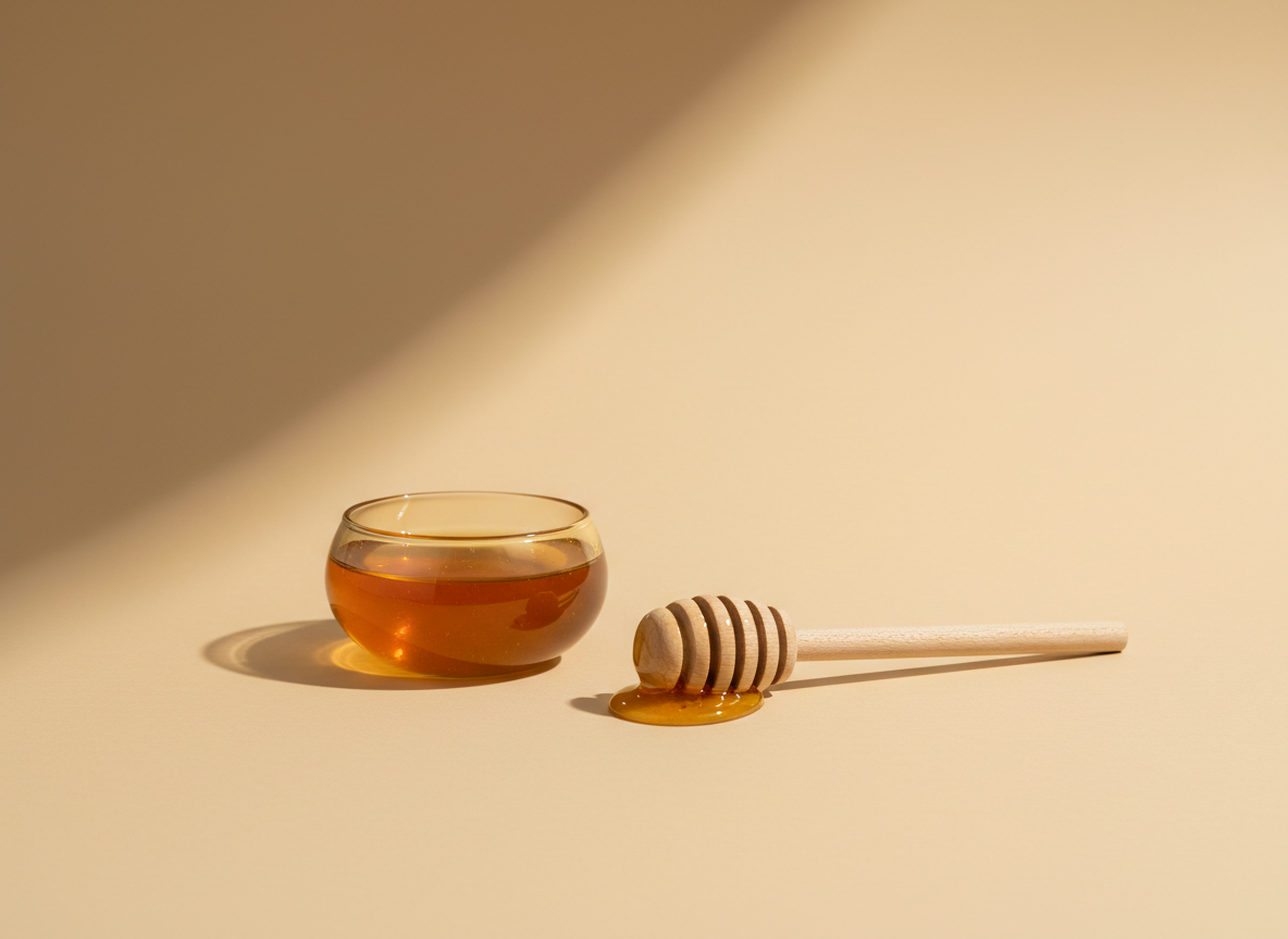 Golden manuka honey in a glass dish with a wooden dipper
