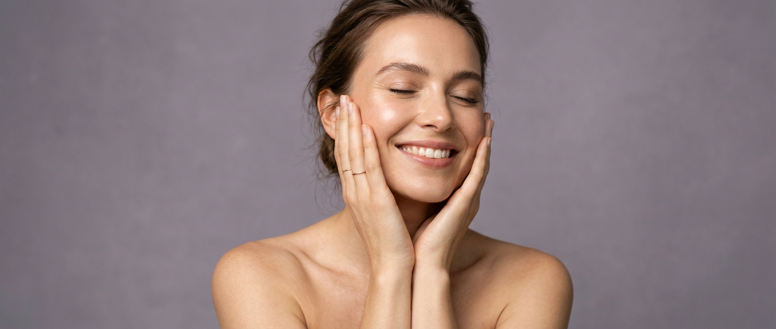 Smiling woman with glowing skin gently touching her face