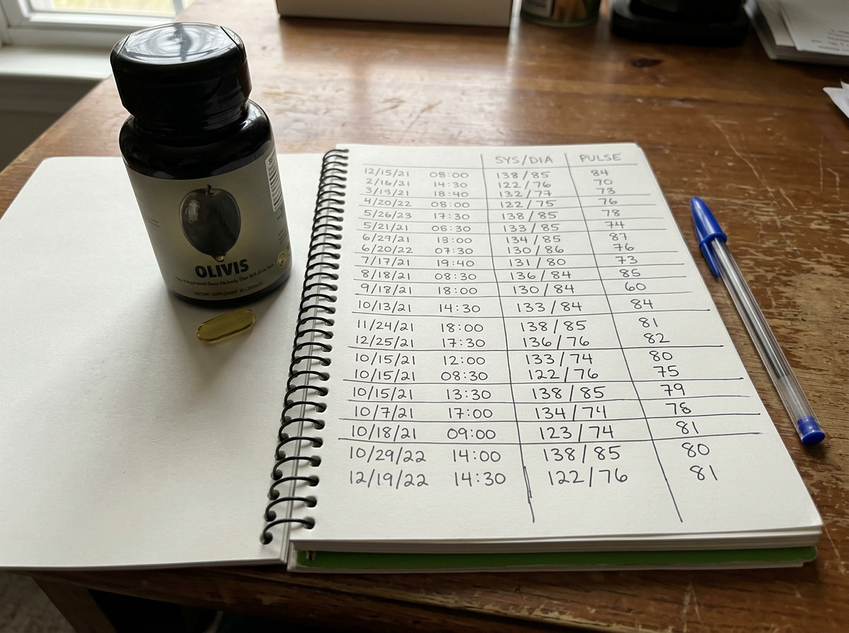 Gary's handwritten blood pressure log next to his bottle of Olivis