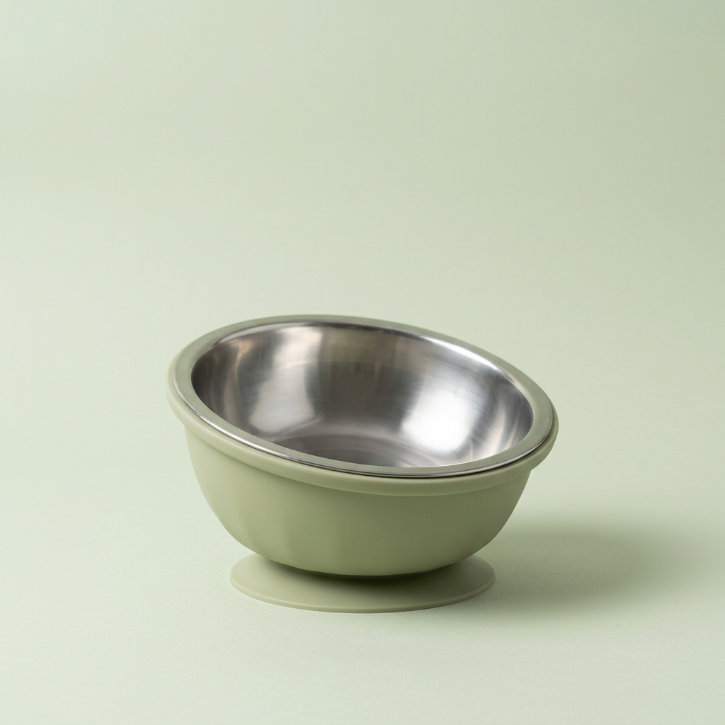 The tilted bowl with its stainless steel insert on a soft sage-green backdrop