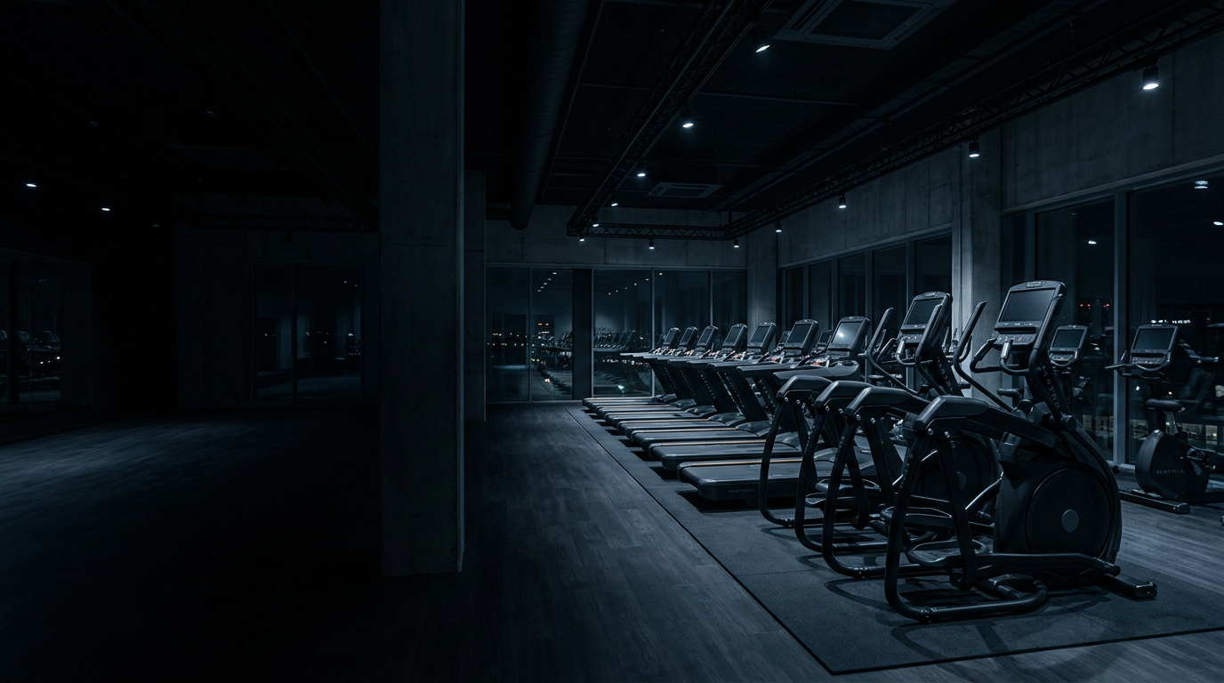 Commercial treadmills and ellipticals in a dimly lit gym