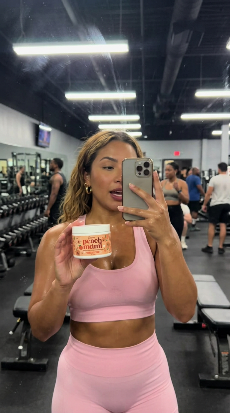 Gym mirror review in a baby-pink set holding Peach Mami