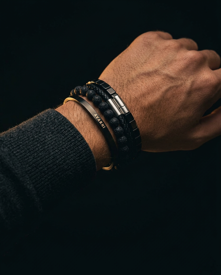 Close-up of a man's wrist stacked with Avarni black cuff, lava stone, braided leather and link bracelets